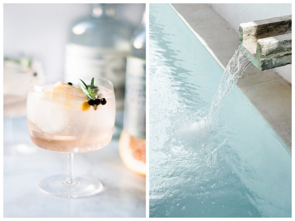 Glass of gin next to water fall in swimming pool