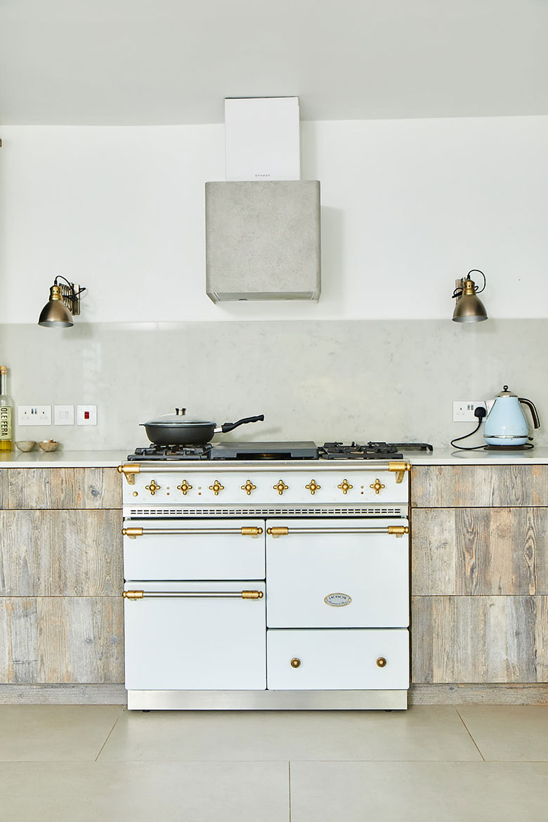 Classic white Macon range cooker by Lacanche with concrete canopy and driftwood kitchen cabinets