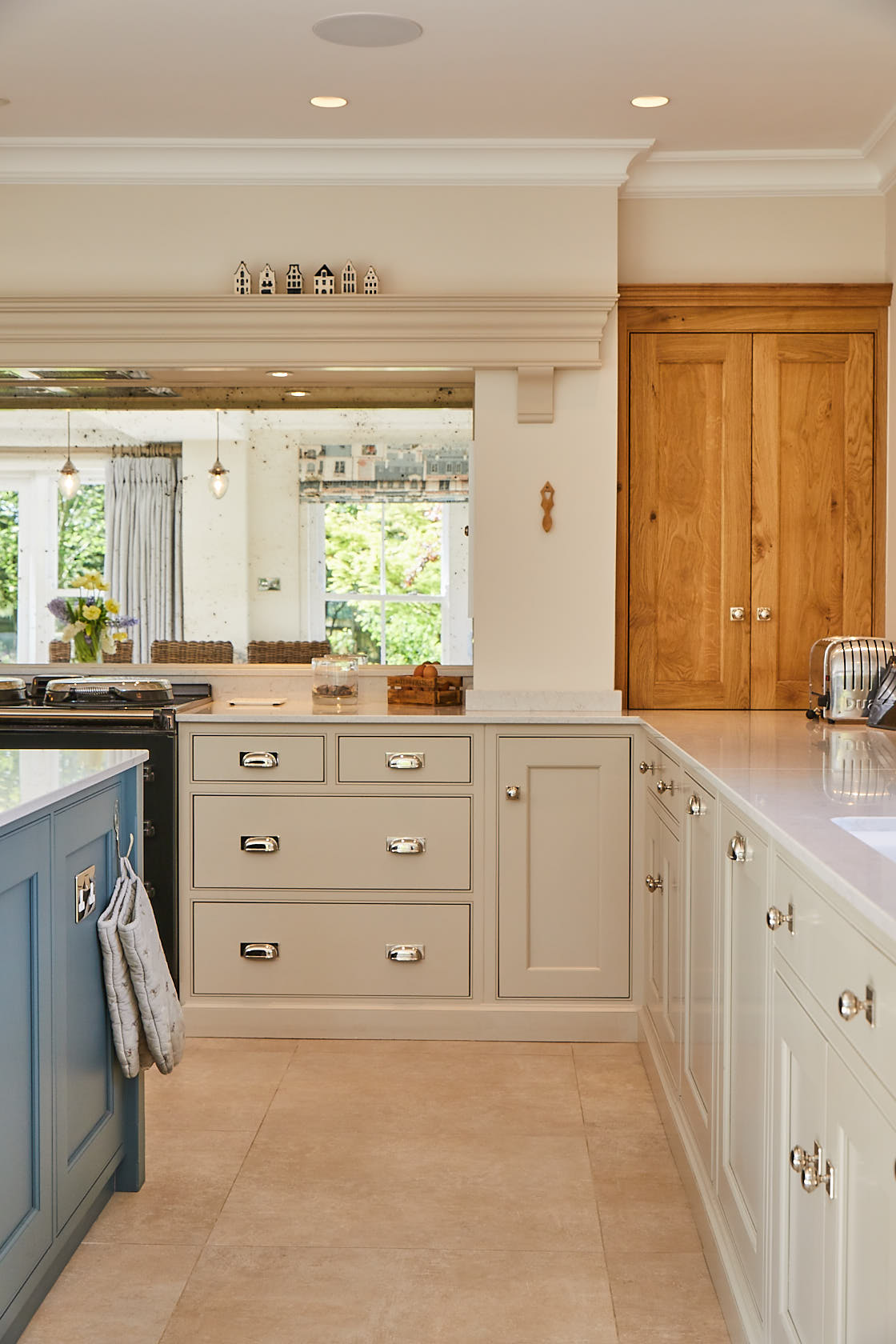 Painted cream kitchen cabinets contrast with solid oak traditional wall unit nestled in alcove