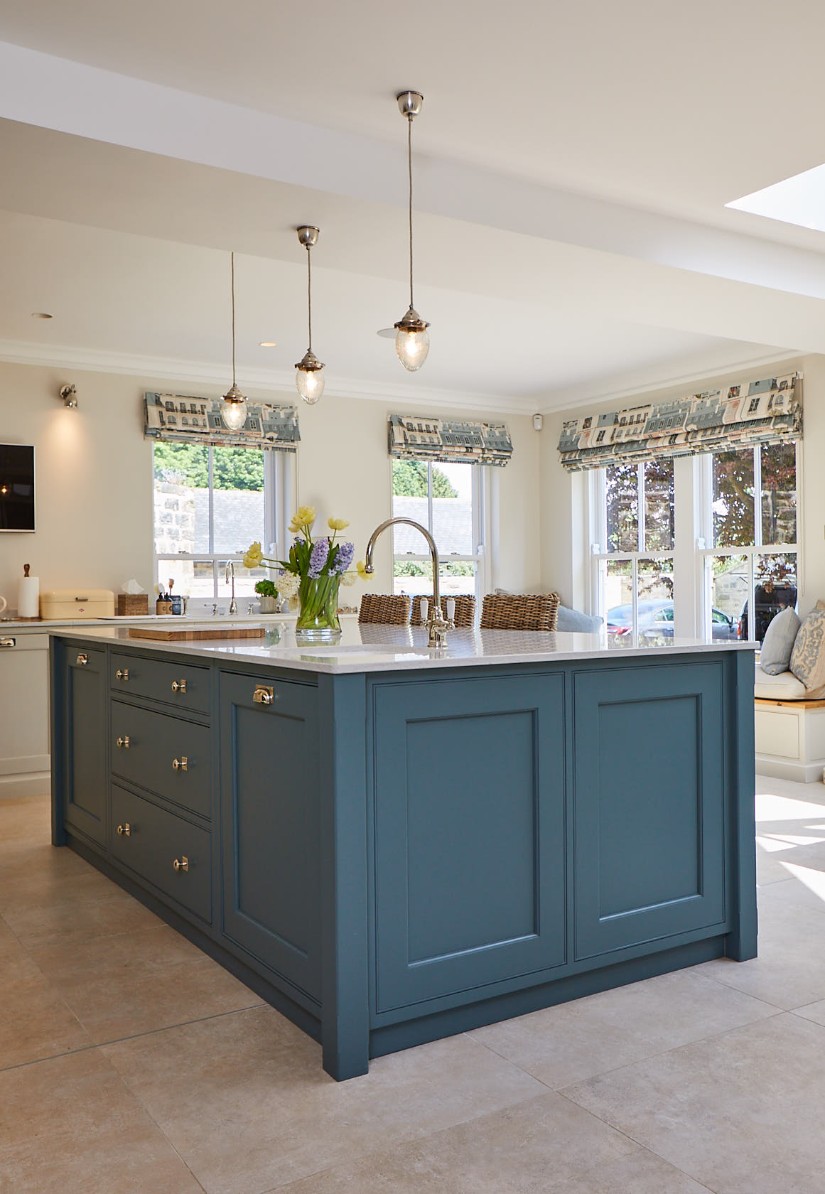 Glass pendant lights above green island with under mount stainless steel sink