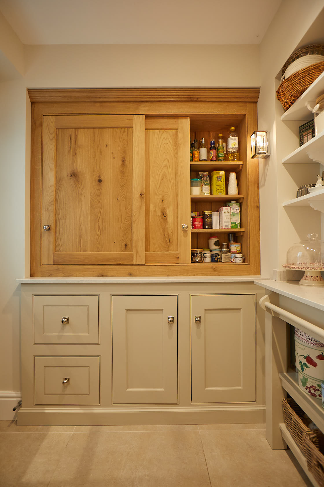 Sliding oak shaker doors in pantry with painted cream base cabinets