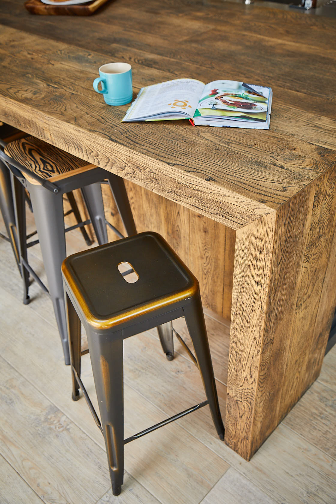 Industrial metal bar stool next to hand aged oak breakfast bar