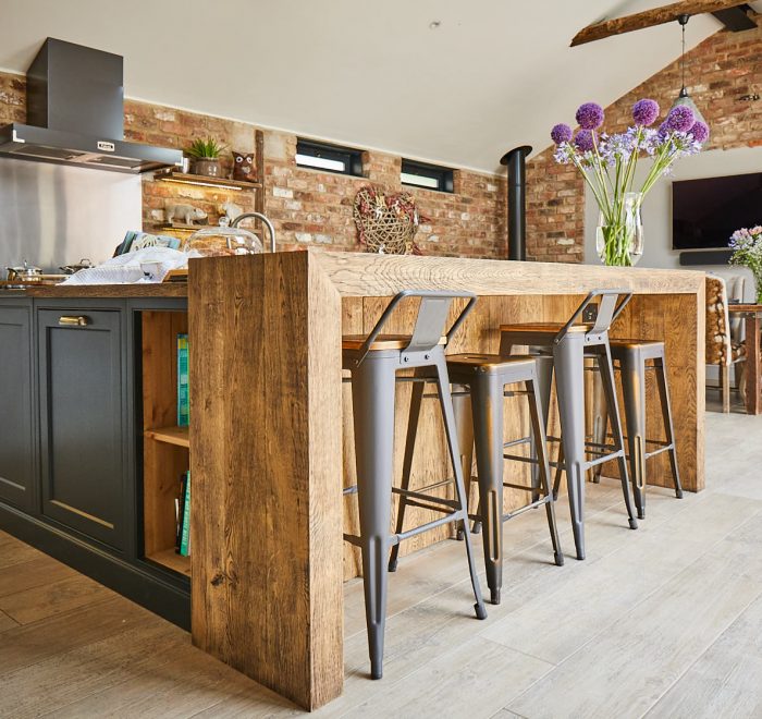 Open unit next to oak chunky breakfast bar and industrial metal bar stools