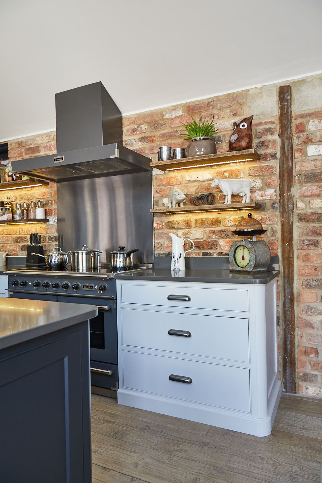 Grey range cooker with stainless steel extractor against exposed brick wall