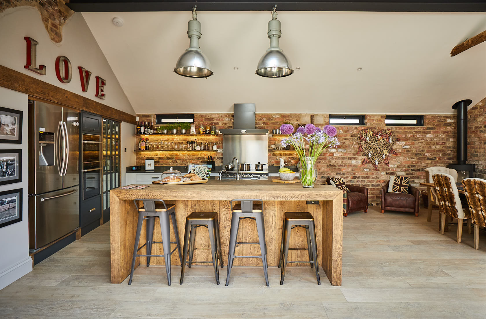 Large reclaimed pig lamps shine on engineered oak hand aged breakfast bar and stools