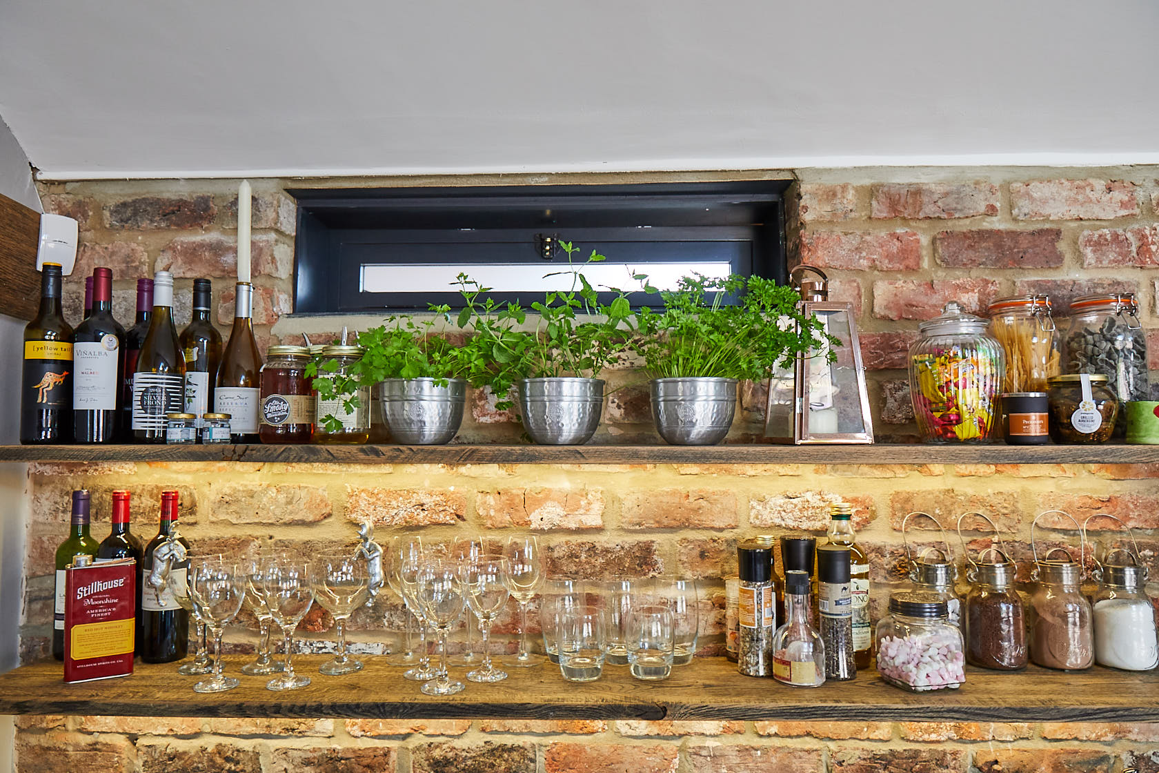Rustic oak shelves with herbs on and exposed brick wall backdrop