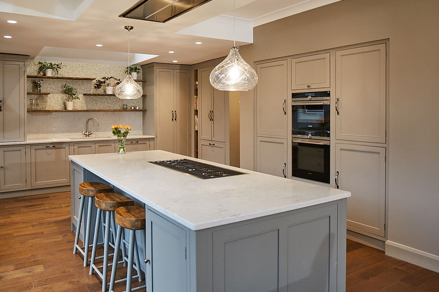 Crystal pendant lights above traditional painted kitchen island with white quartz worktop
