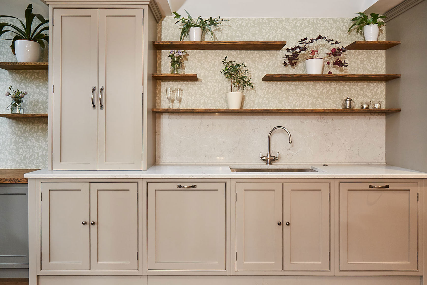 Traditional kitchen sink run with open oak shelves and green wallpaper