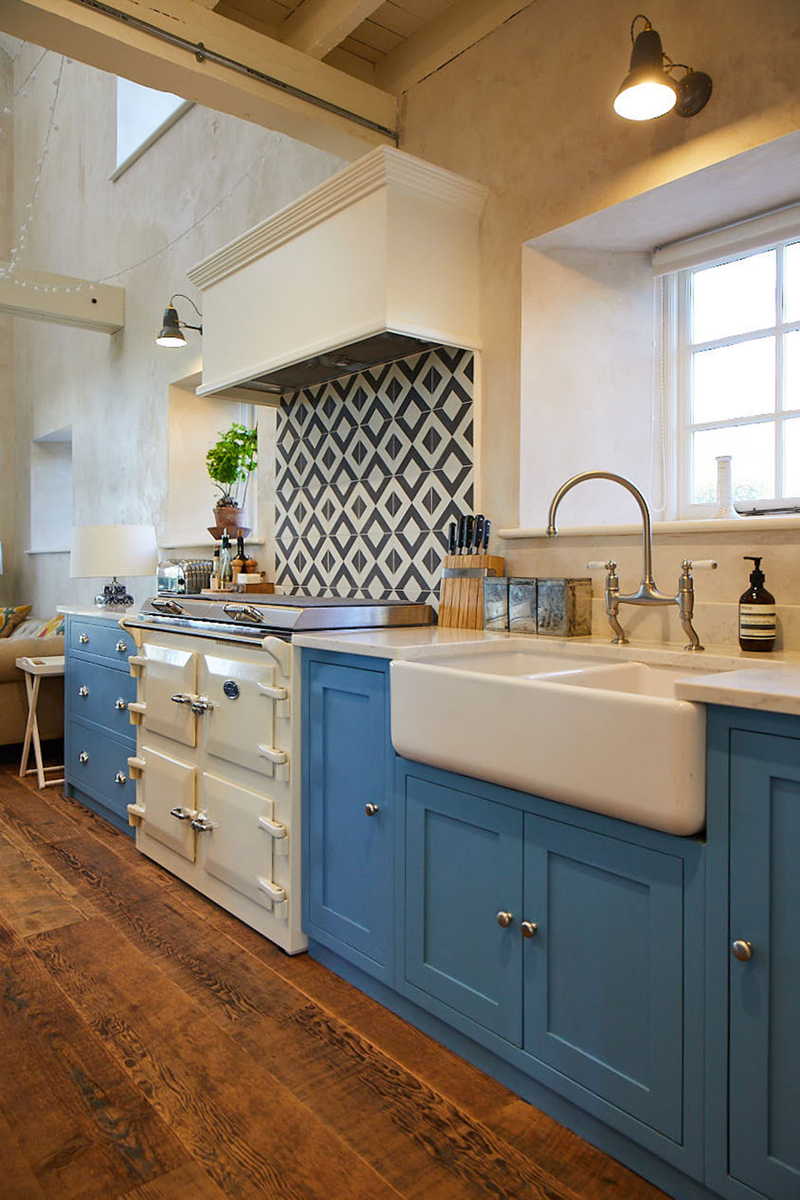 Cream Everhot cooker next to light blue kitchen cabinets and ceramic white double Belfast sink