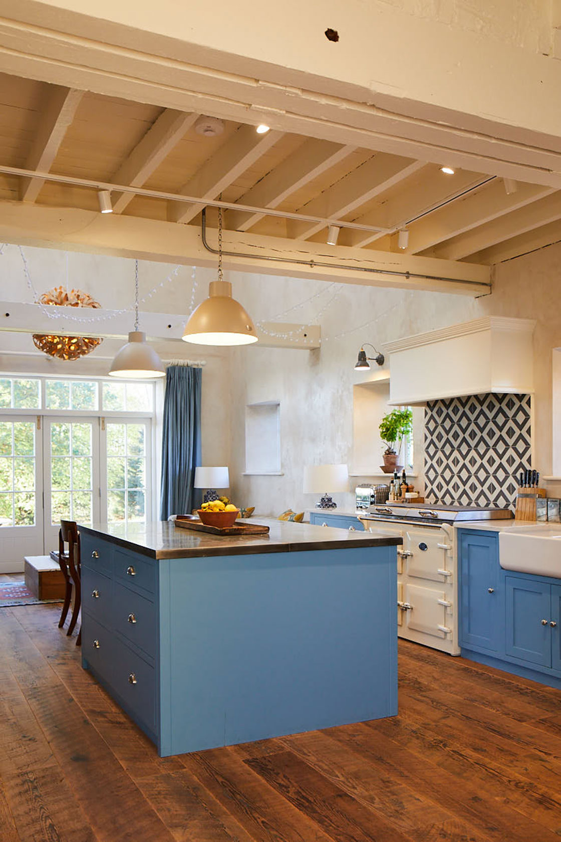 Light blue kitchen island in open plan room with reclaimed pinewood floors