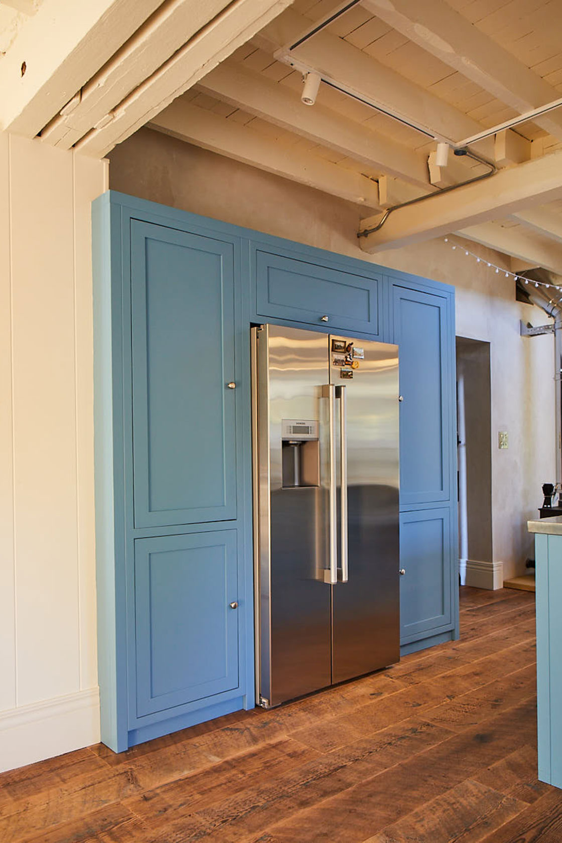 American stainless steel fridge freezer with tall painted light blue kitchen cabinets