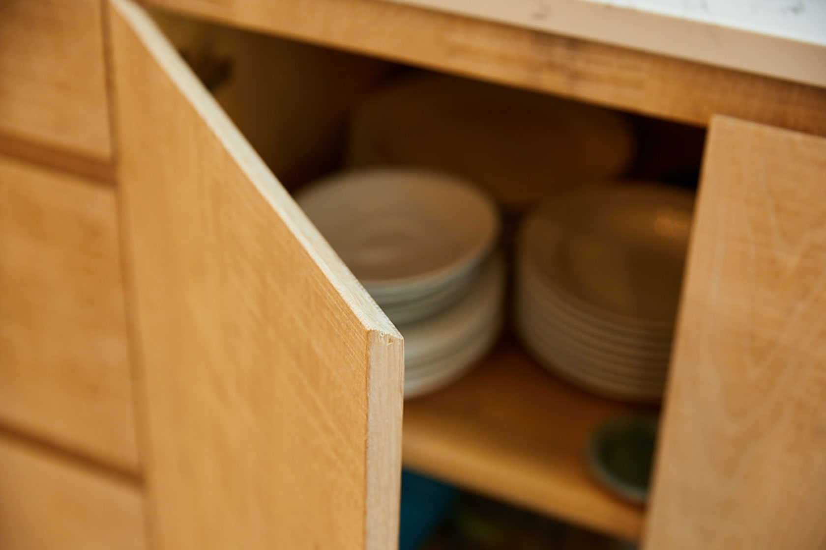 Close up chamfer handle built in to limed oak slab kitchen door