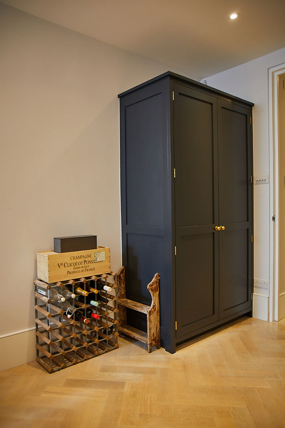 Tall dark blue larder cabinet next to open wine rack