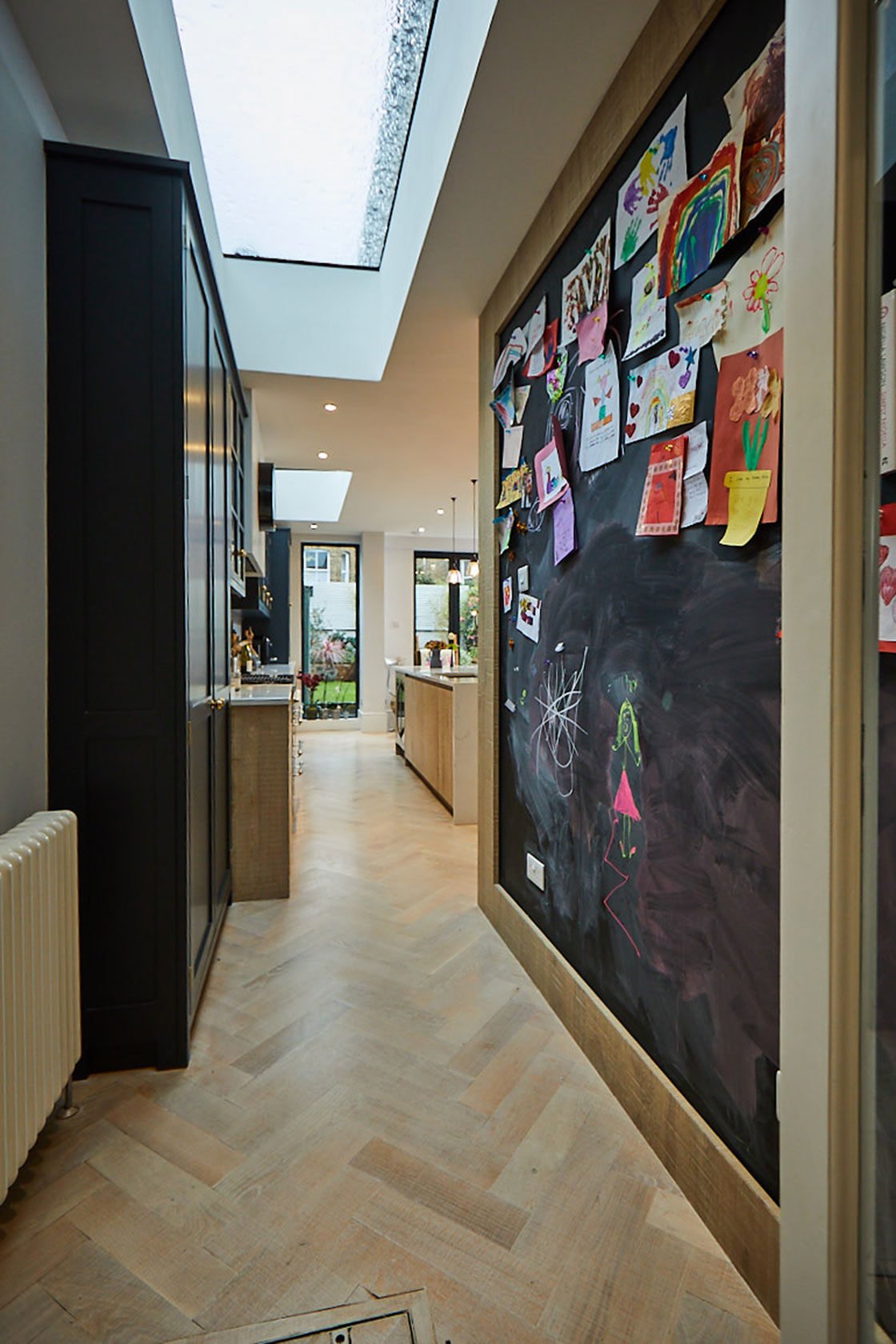 Large black board on kitchen wall filled with notes and scribbles