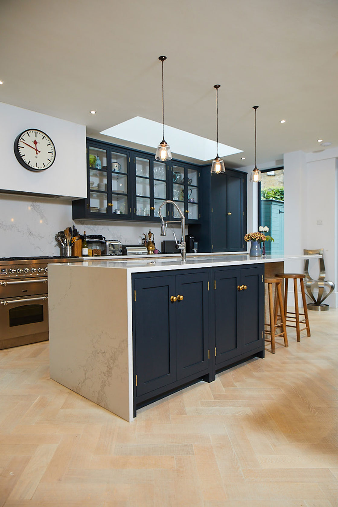 Dark blue double doors on kitchen island with white caesartone worktop and parquet wood floor