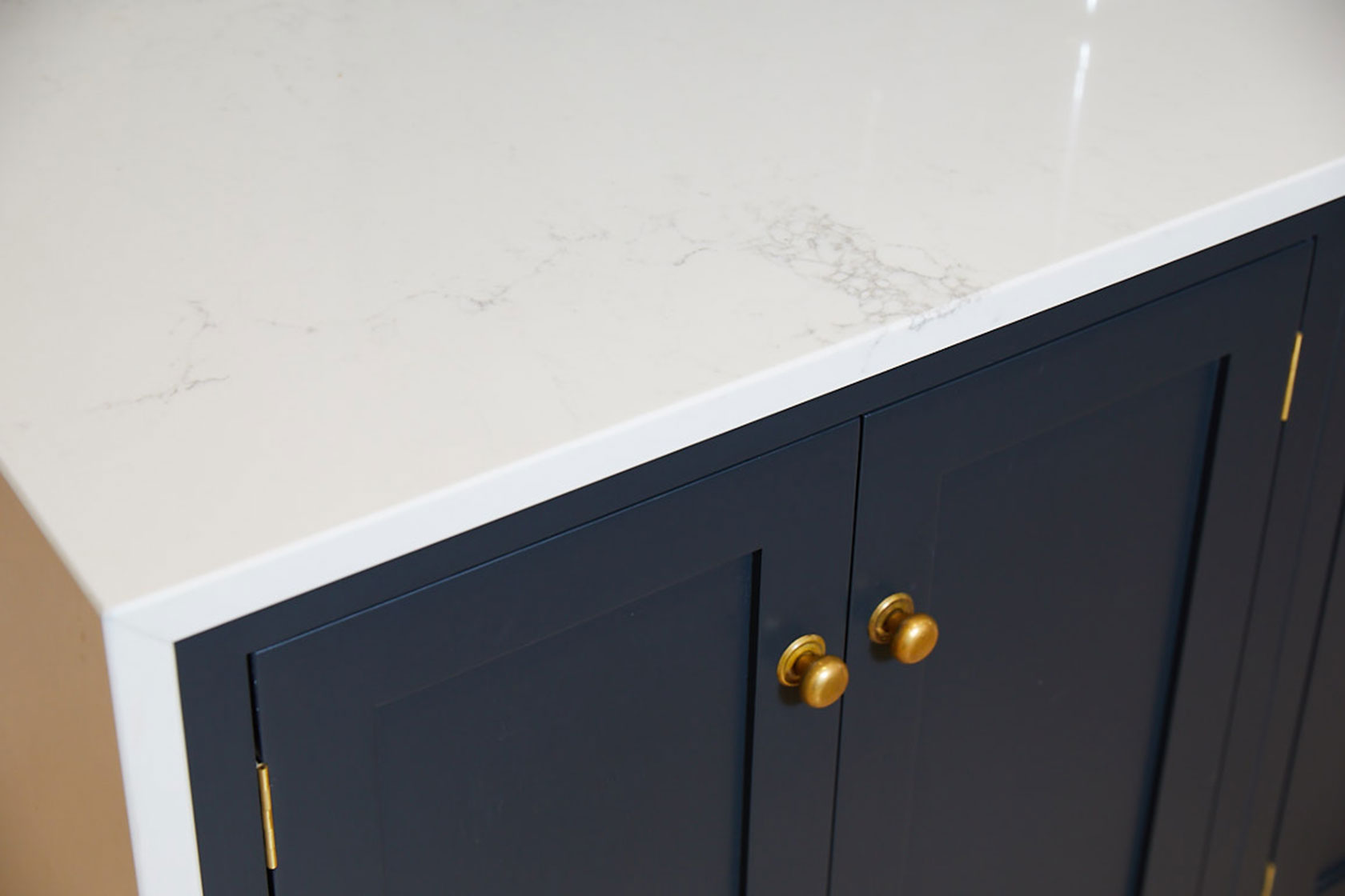 Caesarstone worktop sits on bespoke shaker cabinets with burnt brass knobs