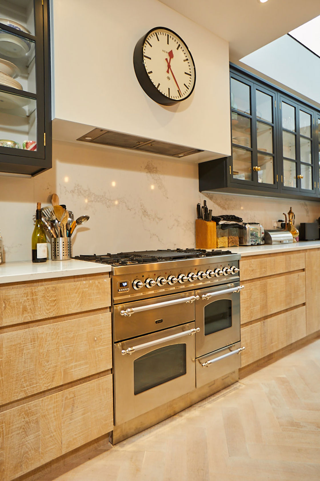 Stainless steel range cooker sits in between limed oak kitchen cabinets with floating minimal white canopy