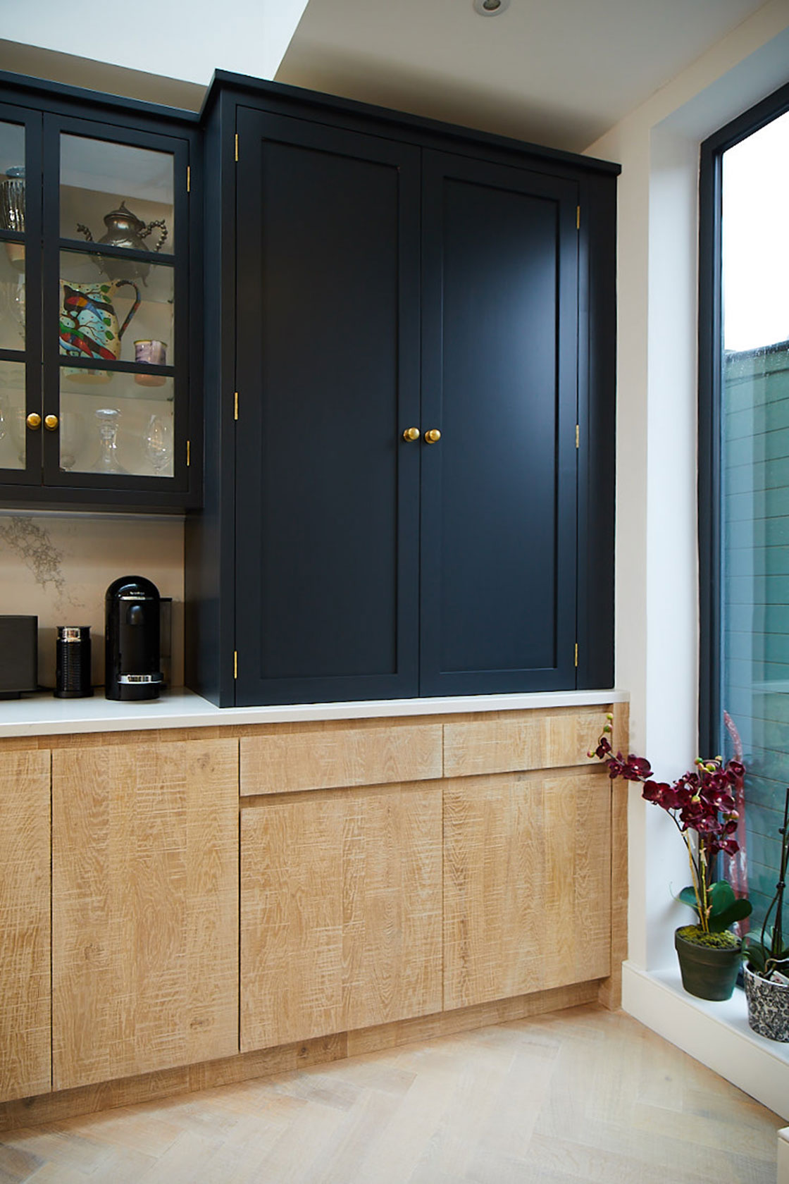 Dark blue shaker wall cabinets sit on Caesarstone worktop with limed oak slab base units below