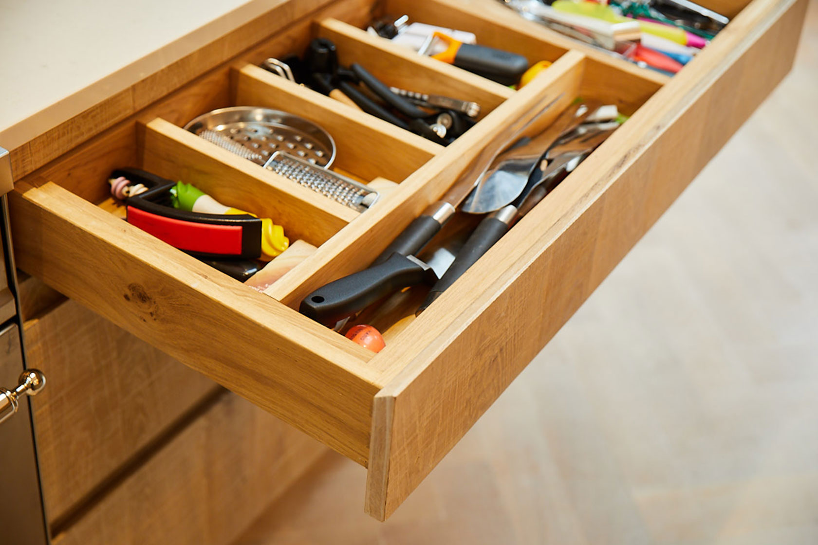 Solid oak drawer divide filled with knives and utensils