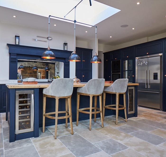 Upholstered bar stools sit under bespoke dark blue kitchen island