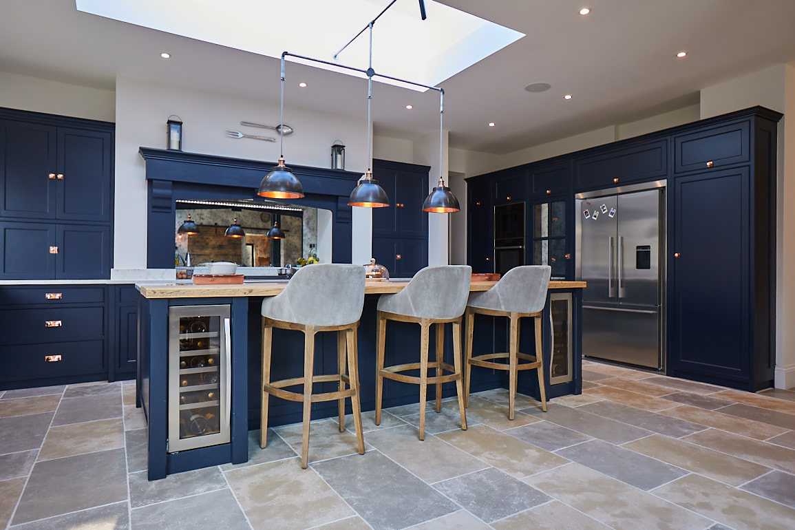 Upholstered bar stools sit under bespoke dark blue kitchen island