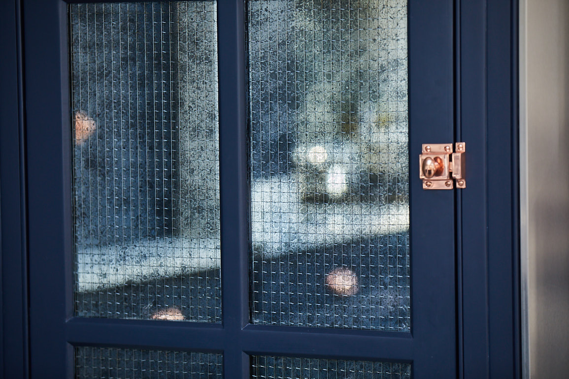 Mirror with wirework reflects dark blue kitchen