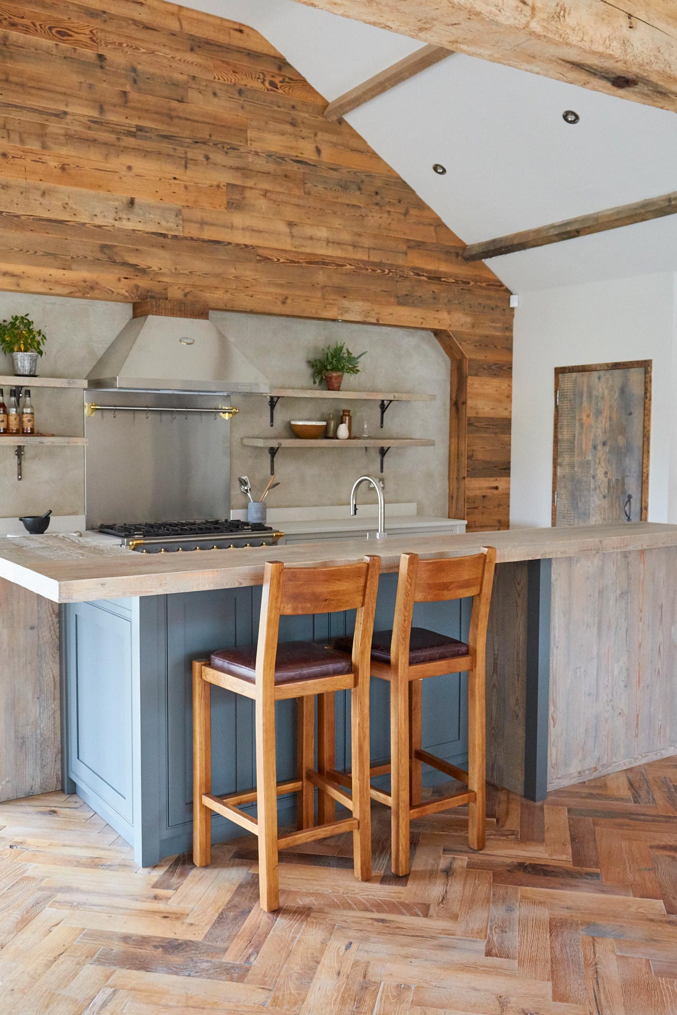 Two oak stools sit under reclaimed pine breakfast bar with painted kitchen cabinets