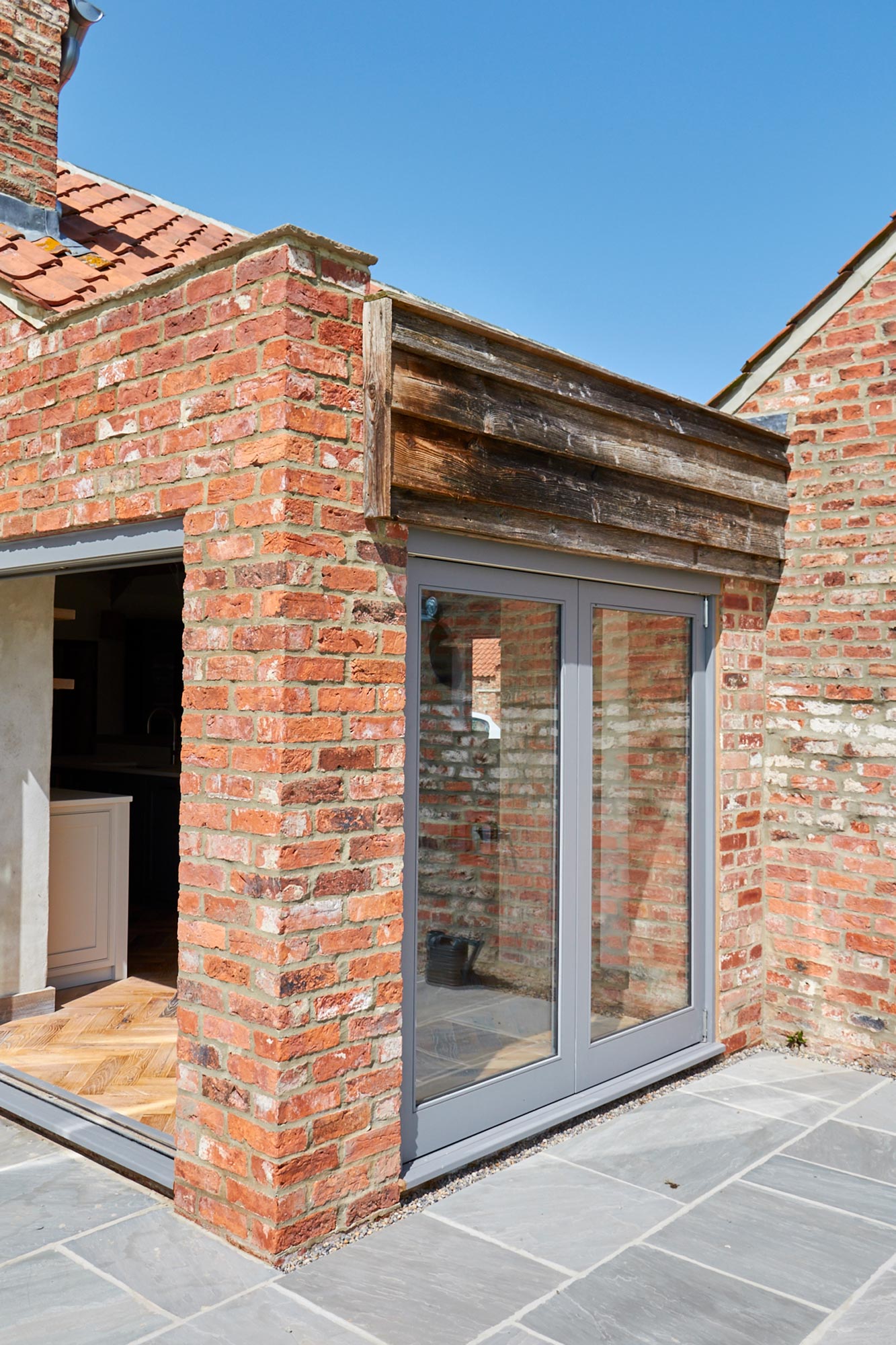 Glass grey patio doors with reclaimed oak cladding above