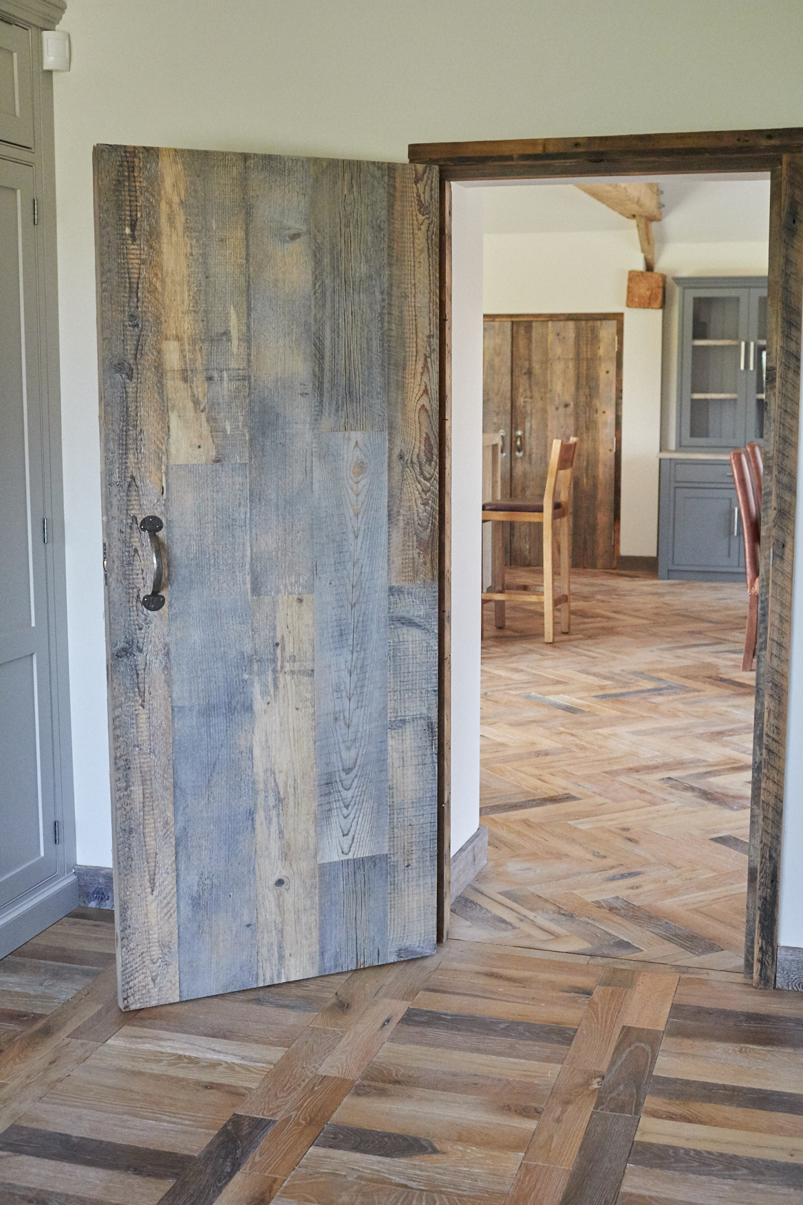 Reclaimed oak parquet flooring running through doorway