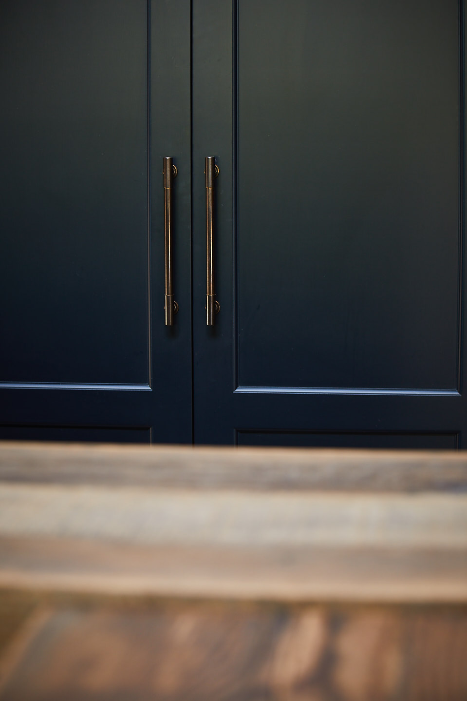 Deep blue kitchen cabinets with aged brass pull handles