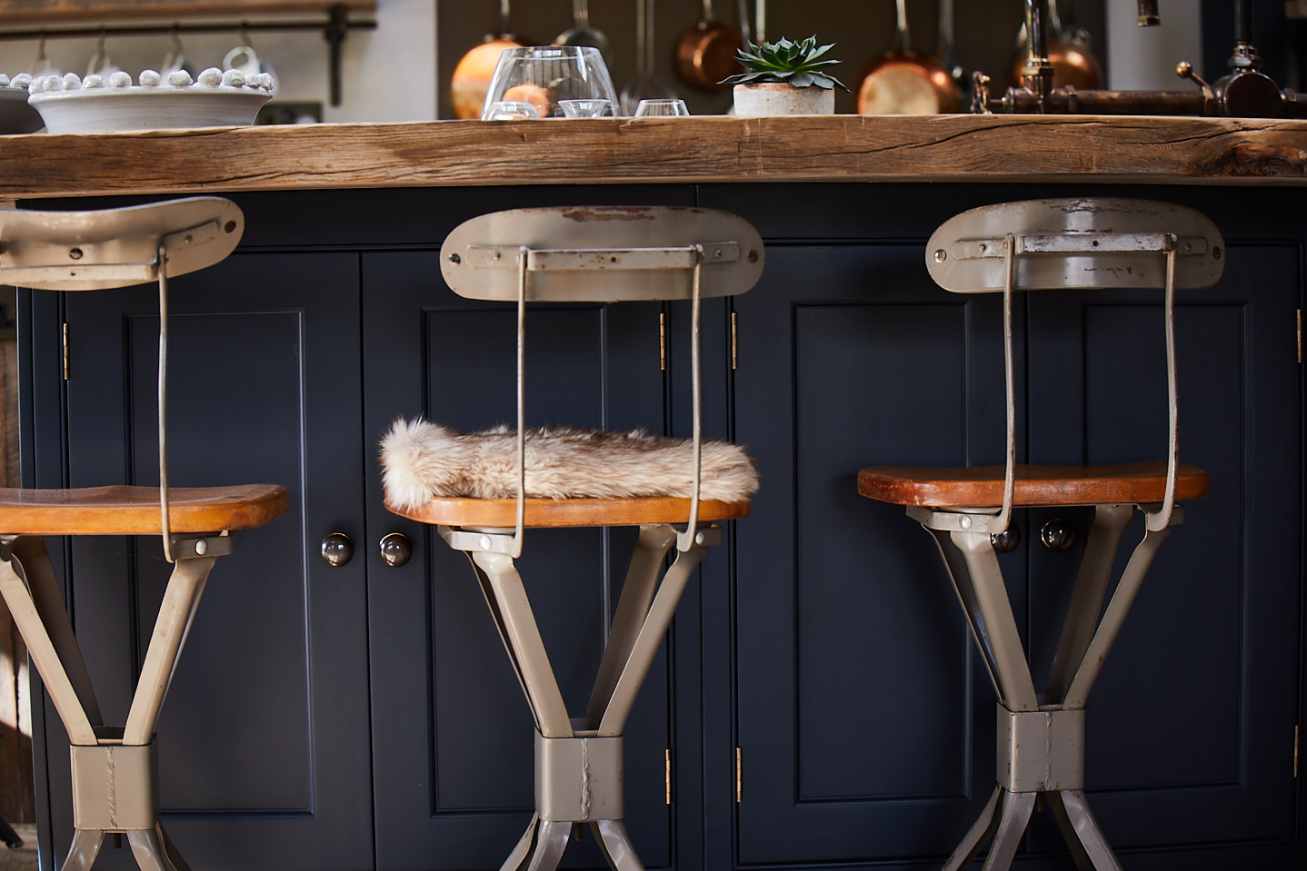 Metal bar stool with wooden seat under painted kitchen cabinet