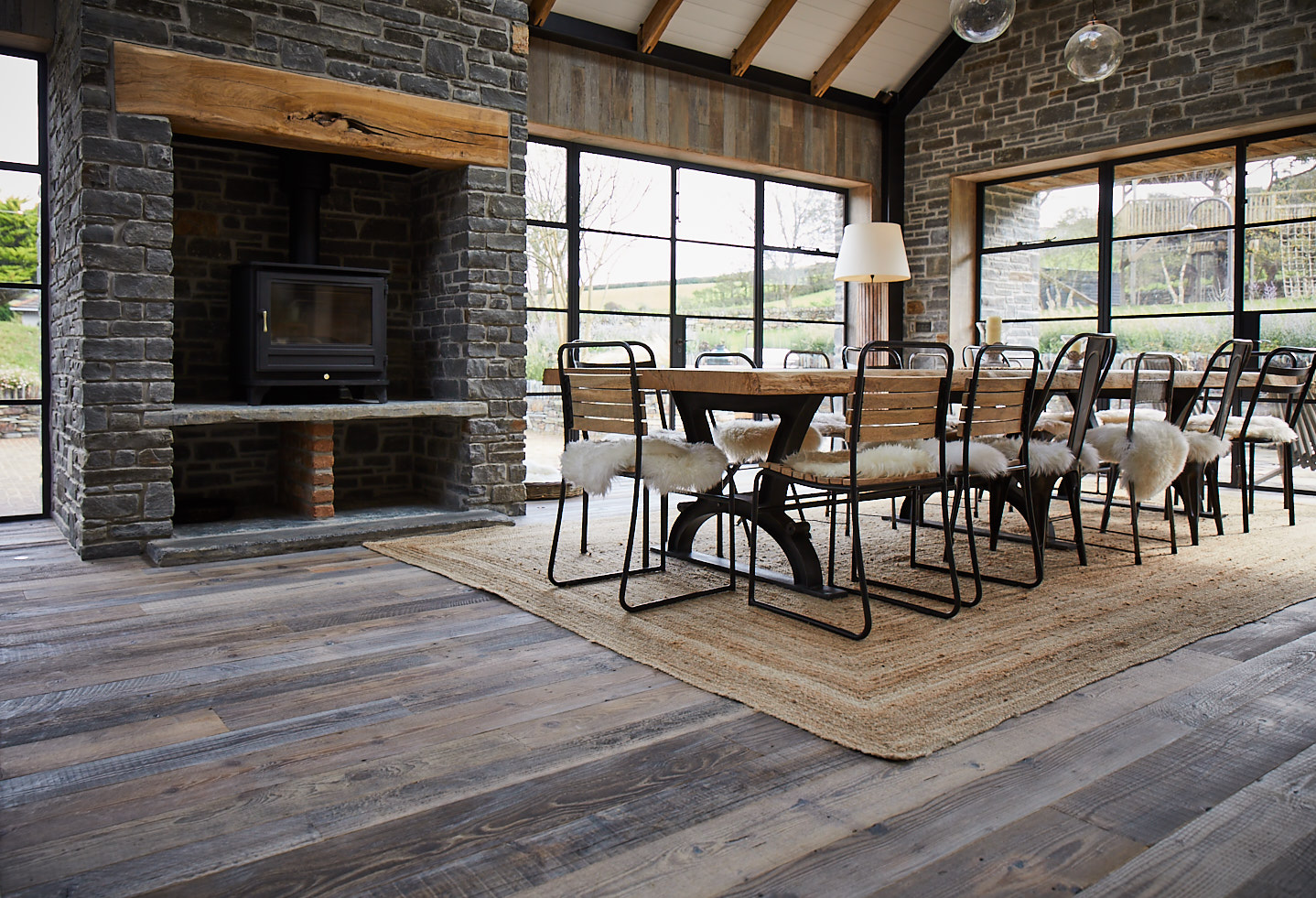 Reclaimed wood flooring with large open fireplace and dining table and chairs