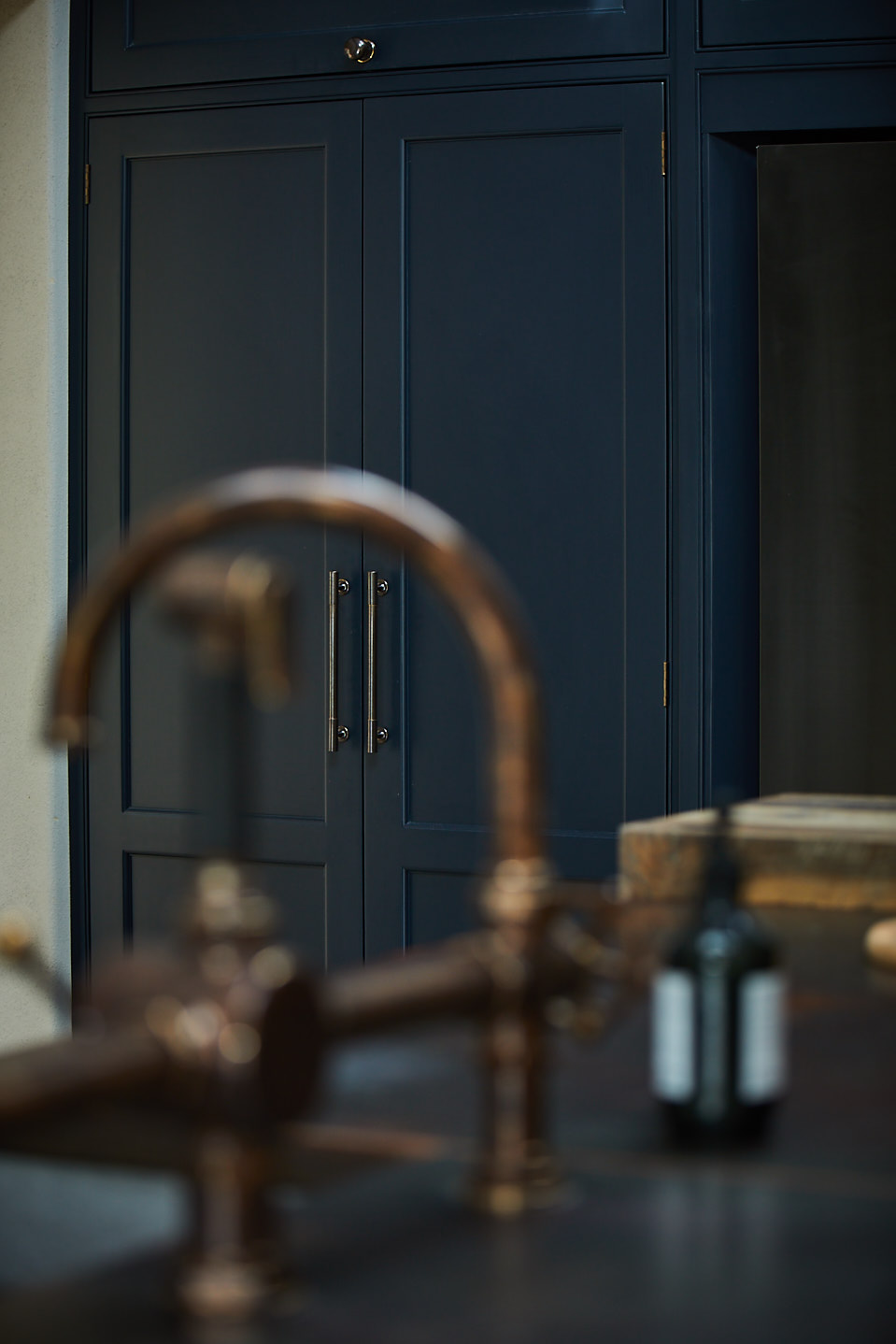 Dark blue painted bespoke kitchen cabinets with aged antique tap
