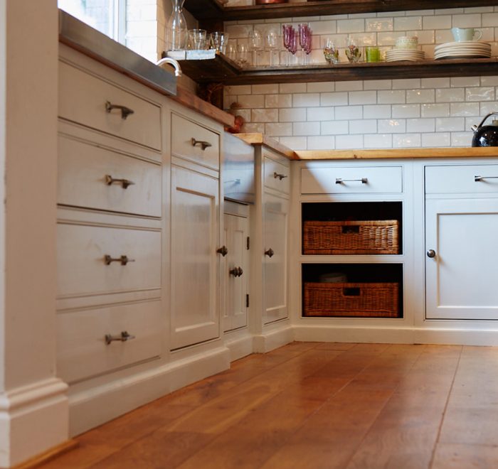 Bespoke kitchen units with reclaimed pine worktop and two exposed wicker baskets