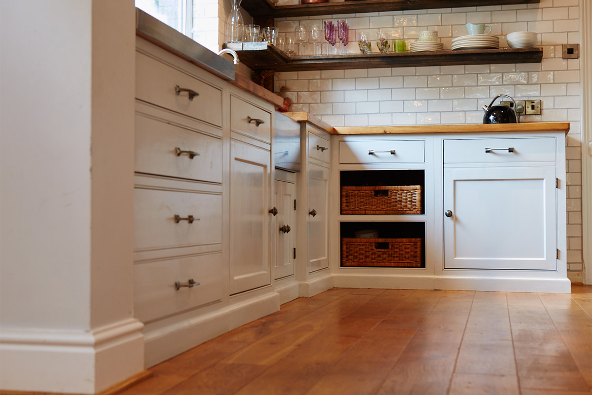 Bespoke kitchen units with reclaimed pine worktop and two exposed wicker baskets