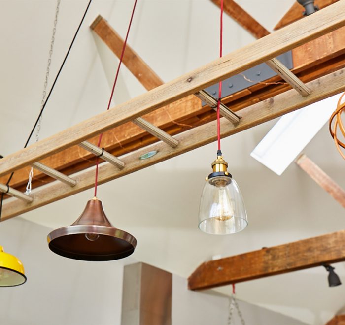 Yellow and copper pendant lights hang in between reclaimed ladder