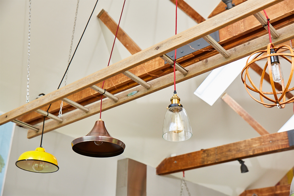 Yellow and copper pendant lights hang in between reclaimed ladder