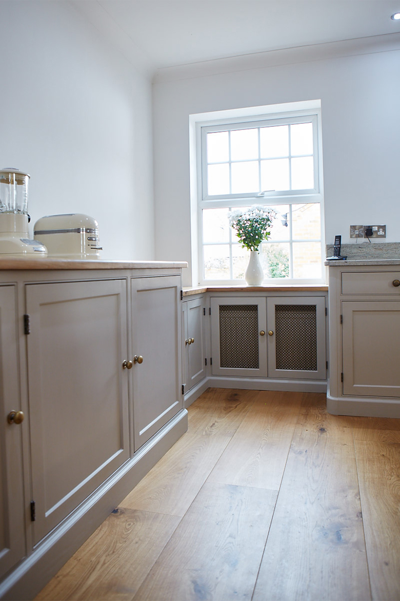 Bespoke radiator cover that looks like a kitchen cabinet with wire mesh panels and solid oak worktop