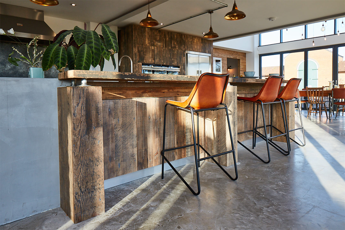 Reclaimed engineered double door units under solid oak breakfast bar and leather bar stools