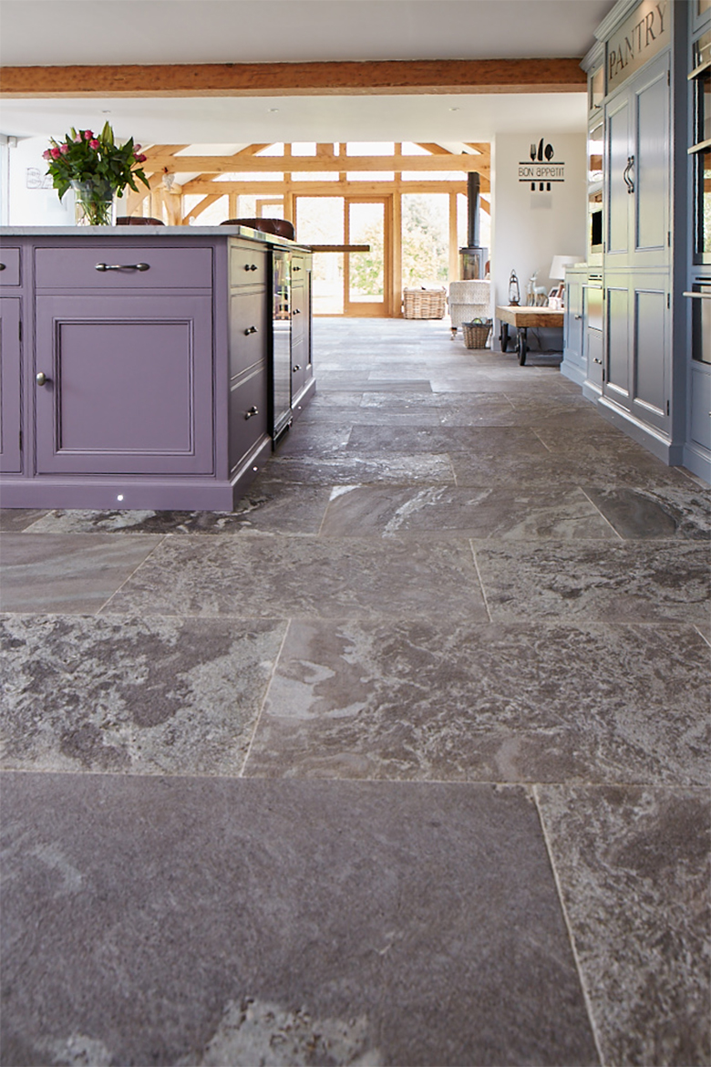 Bespoke purple kitchen island sits on grey stone floor tiles