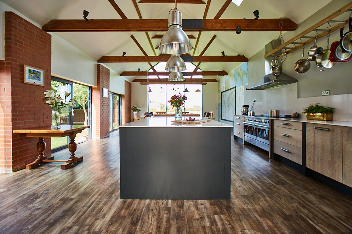 Bespoke kitchen island with Lamp Black Little Greene end panel and stainless steel pendant lights above