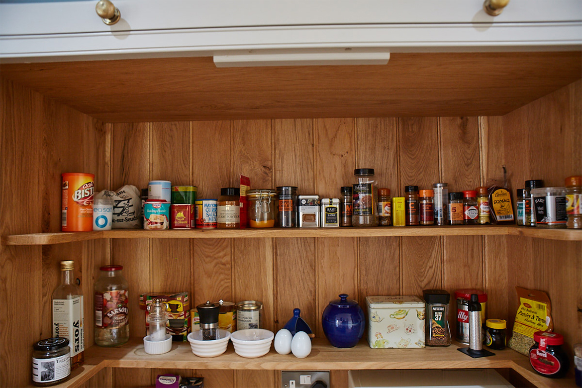 Wrap around larder gallery shelves displaying herbs and spices against solid oak backboards
