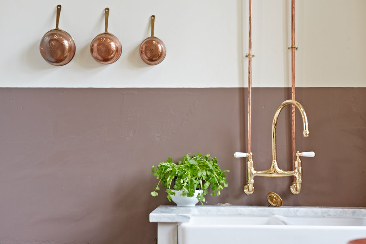 Exposed copper pipes and pans against painted white wall