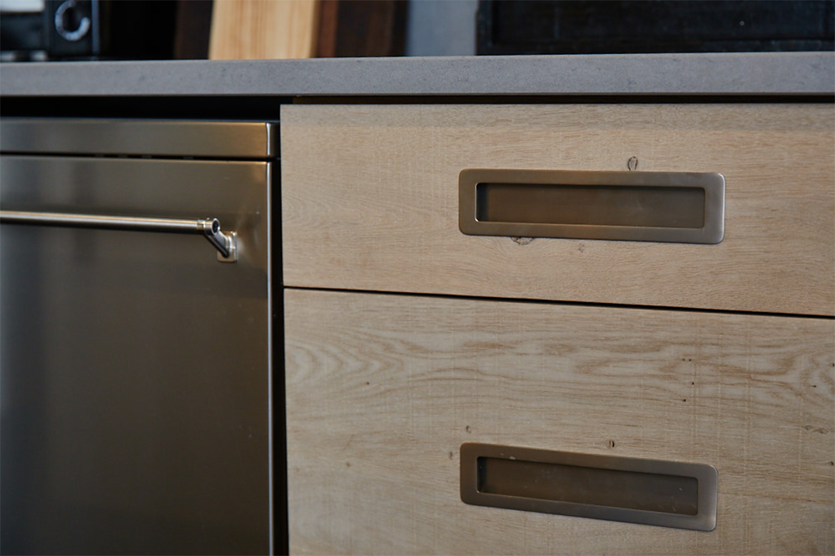Inset brushed kitchen handles against the bespoke oak engineered pan drawer