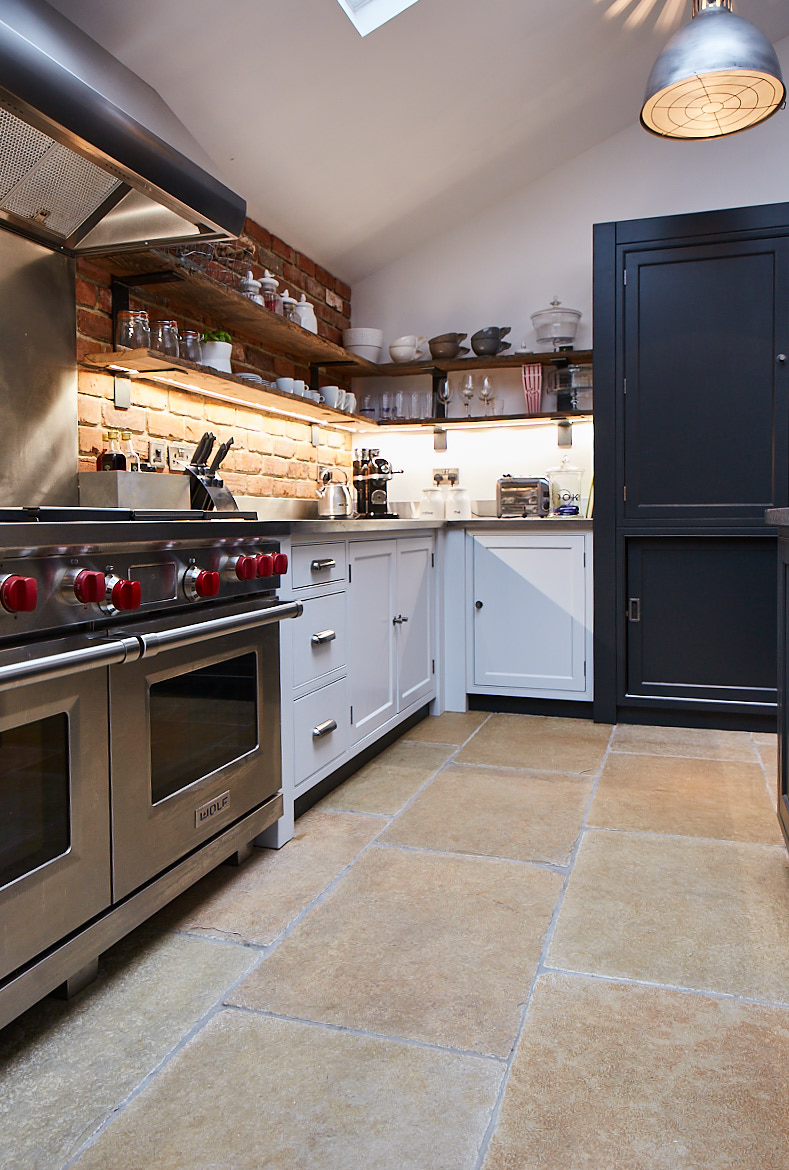 Wolf range cooker and painted bespoke cabinetry set against an exposed brick wall