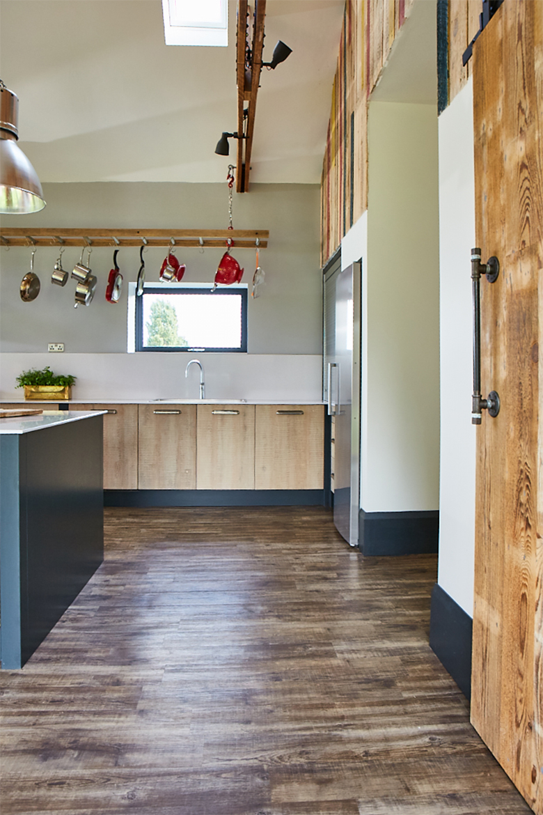 Rustic bespoke kitchen units with integrated stainless steel sink and pans hanging above