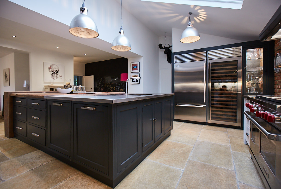 Front of bespoke kitchen island painted in a deep blue to contrast the stainless steel wine fridge and light walls
