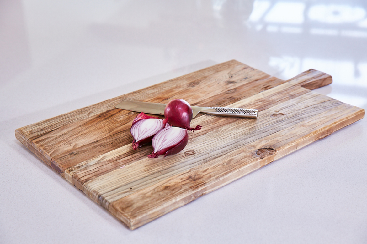 Rustic chopping board with red onion chopped on bespoke dekton kitchen island