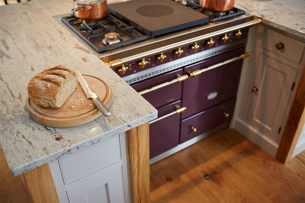 Plum lacanche range cooker sat in between two bespoke painted kitchen cabinets with solid oak legs