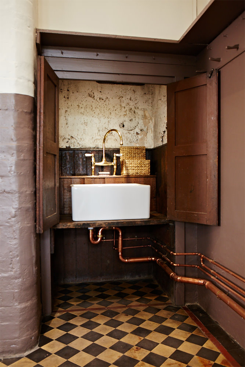 Ceramic sink in pantry cupboard with exposed copper pipes